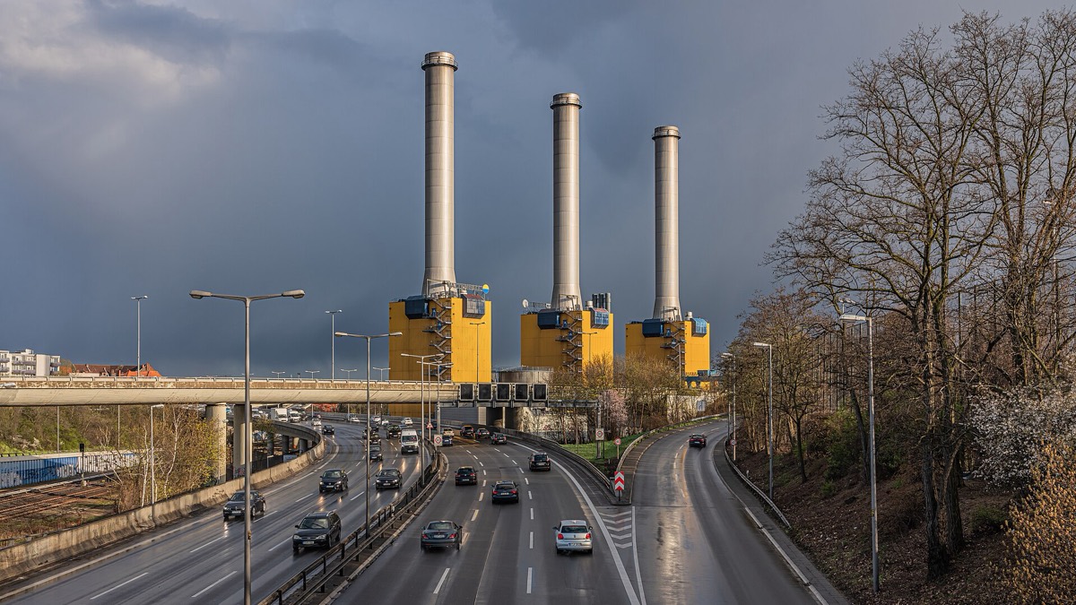 Three towers of a Berlin combined heat and power plant against a storm sky