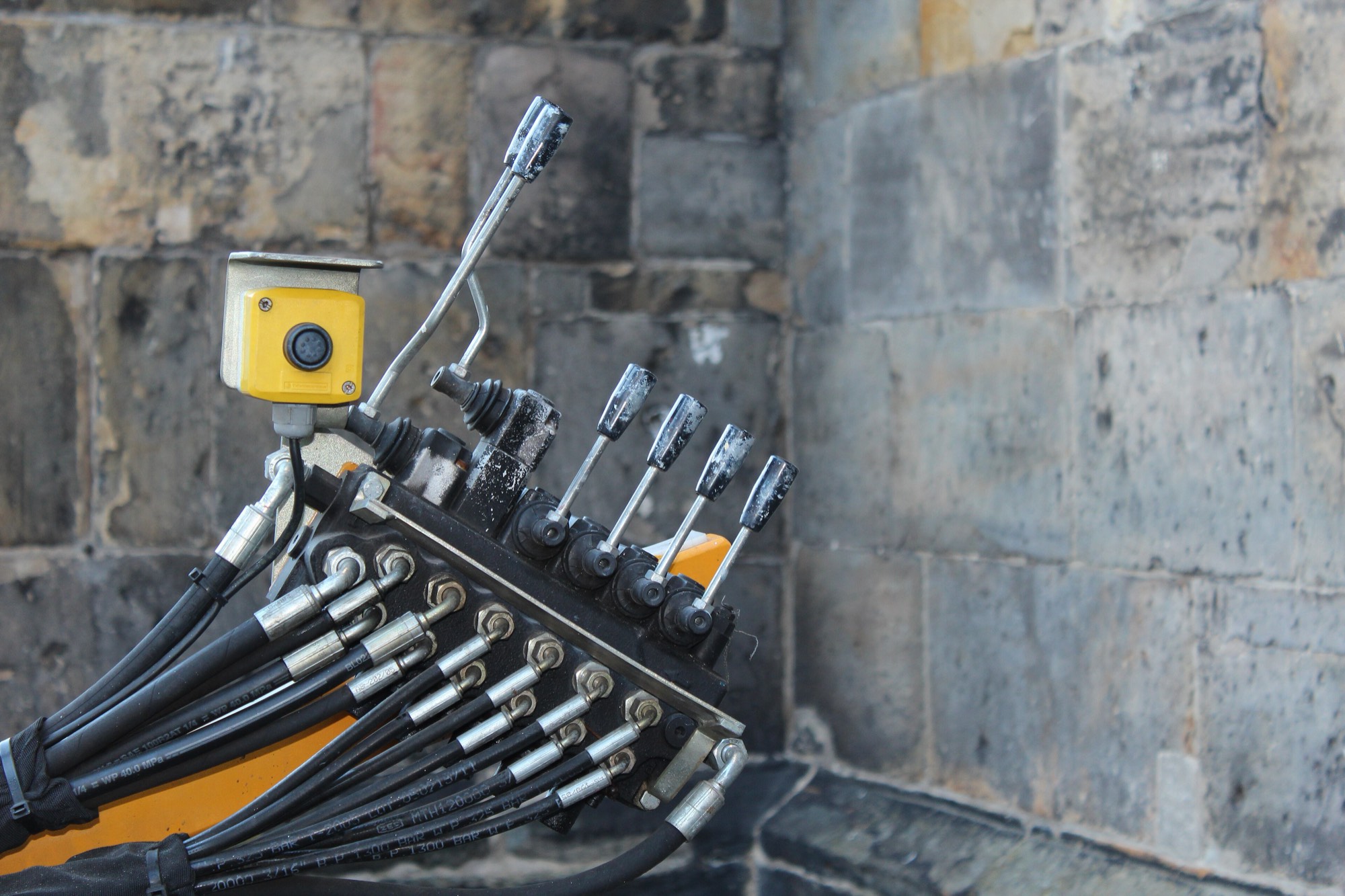 A bank of hydraulic control valves, spool levers above, hose fittings below